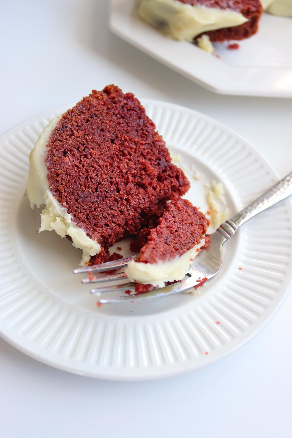 A Nothing Bundt Cake copycat that hits the mark: ultra moist red velvet bundt cake topped with deliciously fluffy cream cheese frosting. This red velvet bundt cake is the easiest from scratch bundt cake you'll ever make! Discover all my secrets to keeping the cake moist and fluffy!