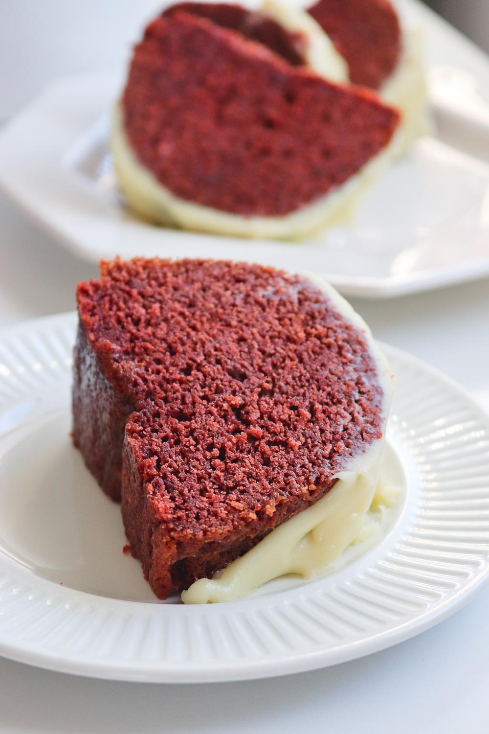 A Nothing Bundt Cake copycat that hits the mark: ultra moist red velvet bundt cake topped with deliciously fluffy cream cheese frosting. This red velvet bundt cake is the easiest from scratch bundt cake you'll ever make! Discover all my secrets to keeping the cake moist and fluffy!