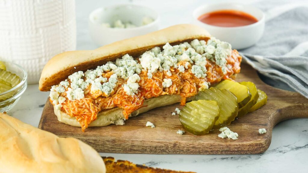 Shredded slow-cooker buffalo chicken cheesesteaks are piled high on a hoagie roll (or brioche buns) and topped with melted cheese and your favorite Buffalo sauce. This sandwich is perfect for a quick and easy meal! 