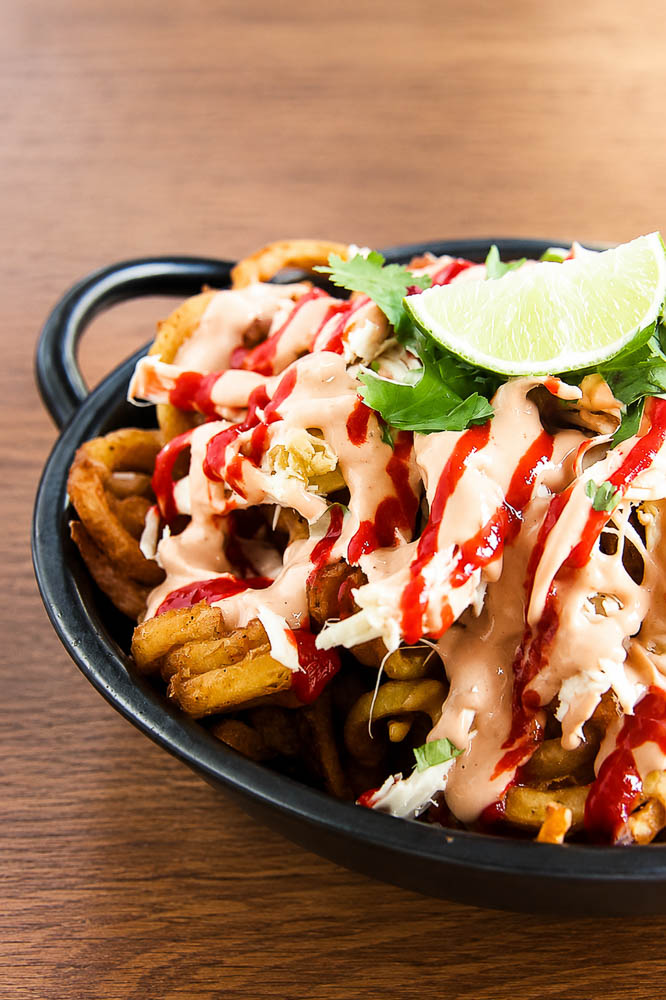 Crispy fries loaded with juicy chicken, smoky adobo sauce, cheese, garlic aioli, and green onions