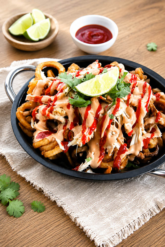 Crispy fries loaded with juicy chicken, smoky adobo sauce, cheese, garlic aioli, and green onions