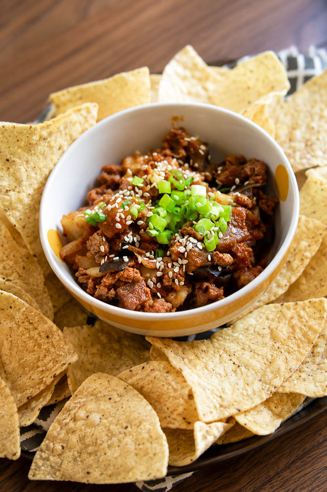 These Kimchi Eggplant Nachos pile crispy tortilla chips with savory ground pork, tender eggplant, and spicy, tangy kimchi for a Korean-inspired appetizer that is loaded with flavor and texture.