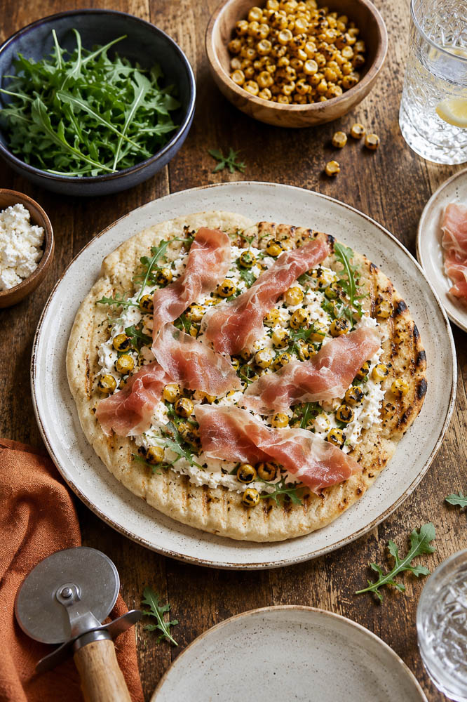 This Roasted Corn Pizza with Cilantro Lime Sauce combines sweet, lightly charred corn with melty mozzarella, salty prosciutto, and a creamy cilantro lime sauce for a homemade pizza that feels fresh, colorful, and a little unexpected.